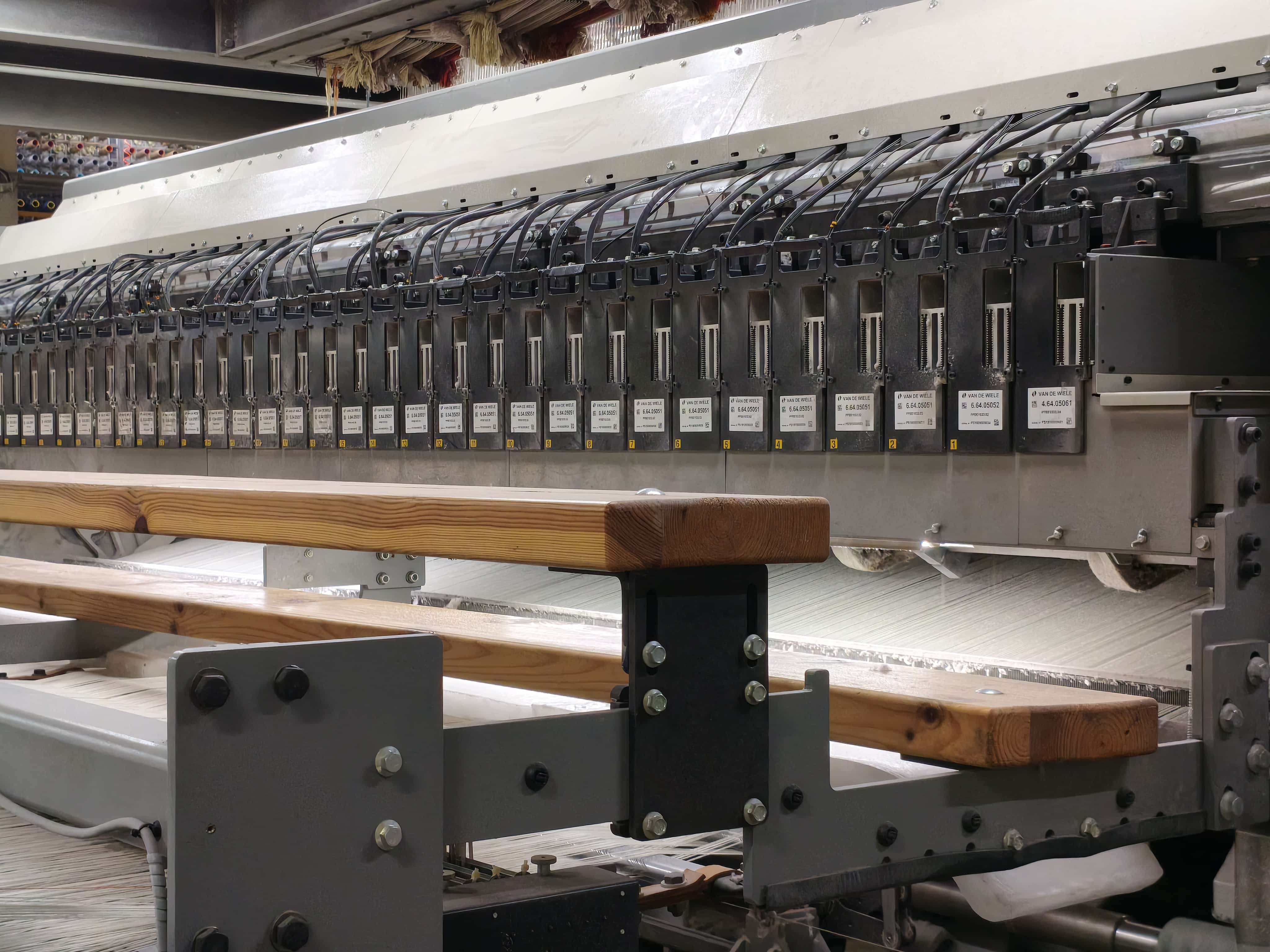 Detailed shot of electronic jacquard control modules on wall-to-wall carpet loom with wooden platform