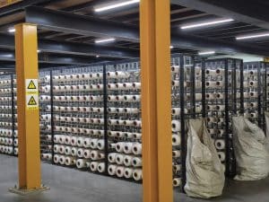 Rows of white yarn cones stored in QIANQIAO’s weaving material warehouse