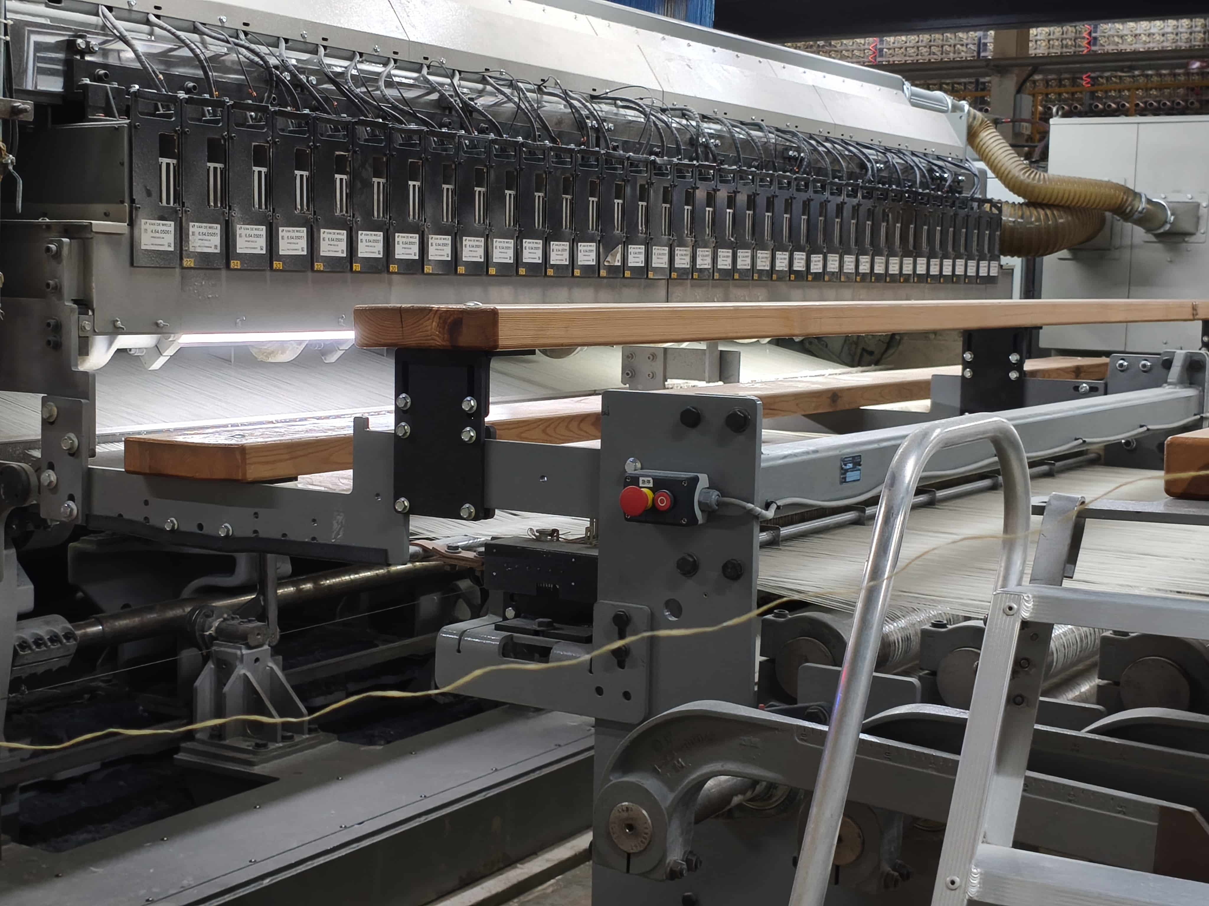 Industrial weaving system with multiple colored yarn strands feeding into wall-to-wall carpet loom