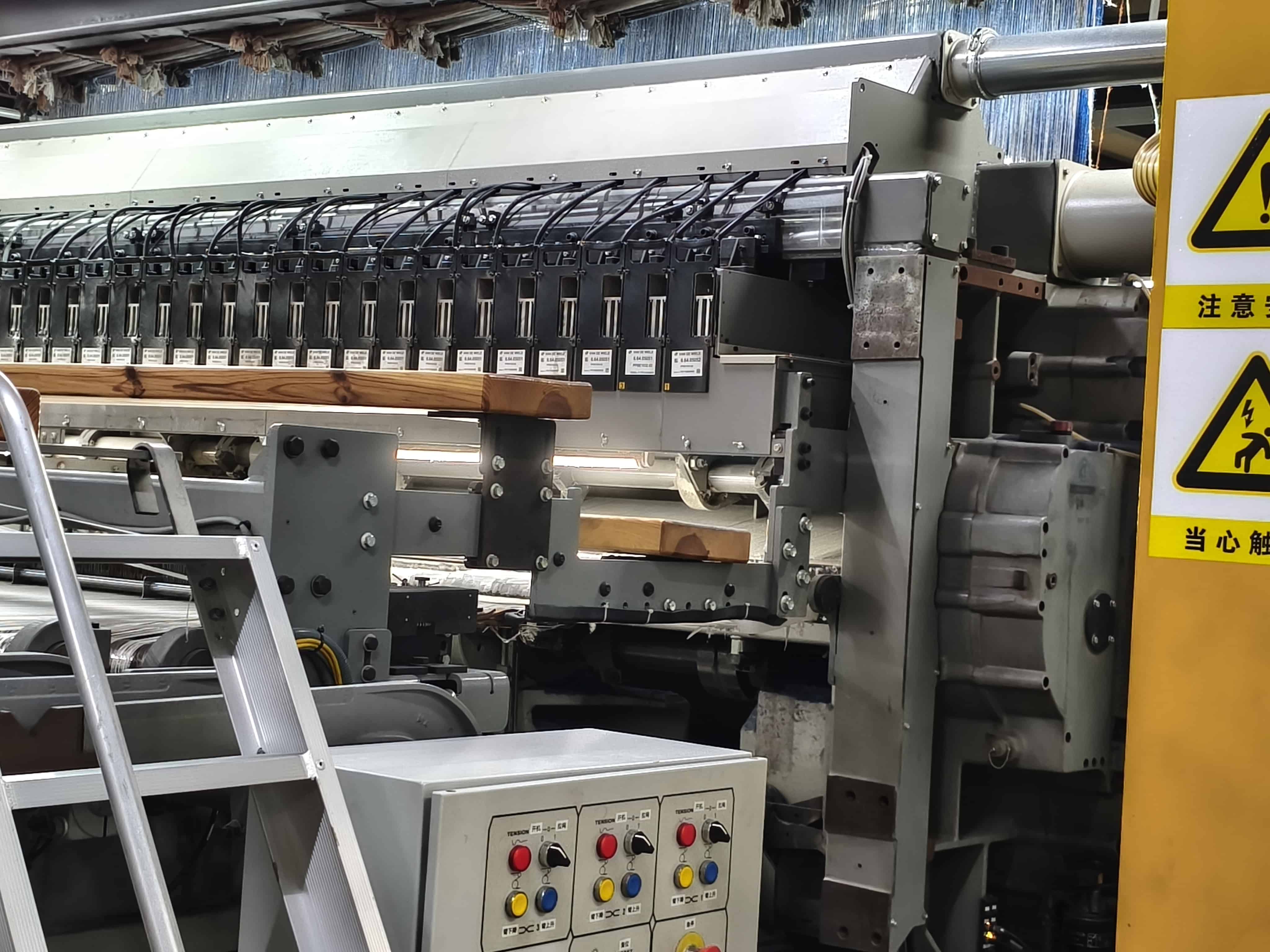 Wall-to-wall carpet loom with programmable jacquard modules and suspended yarn inputs
