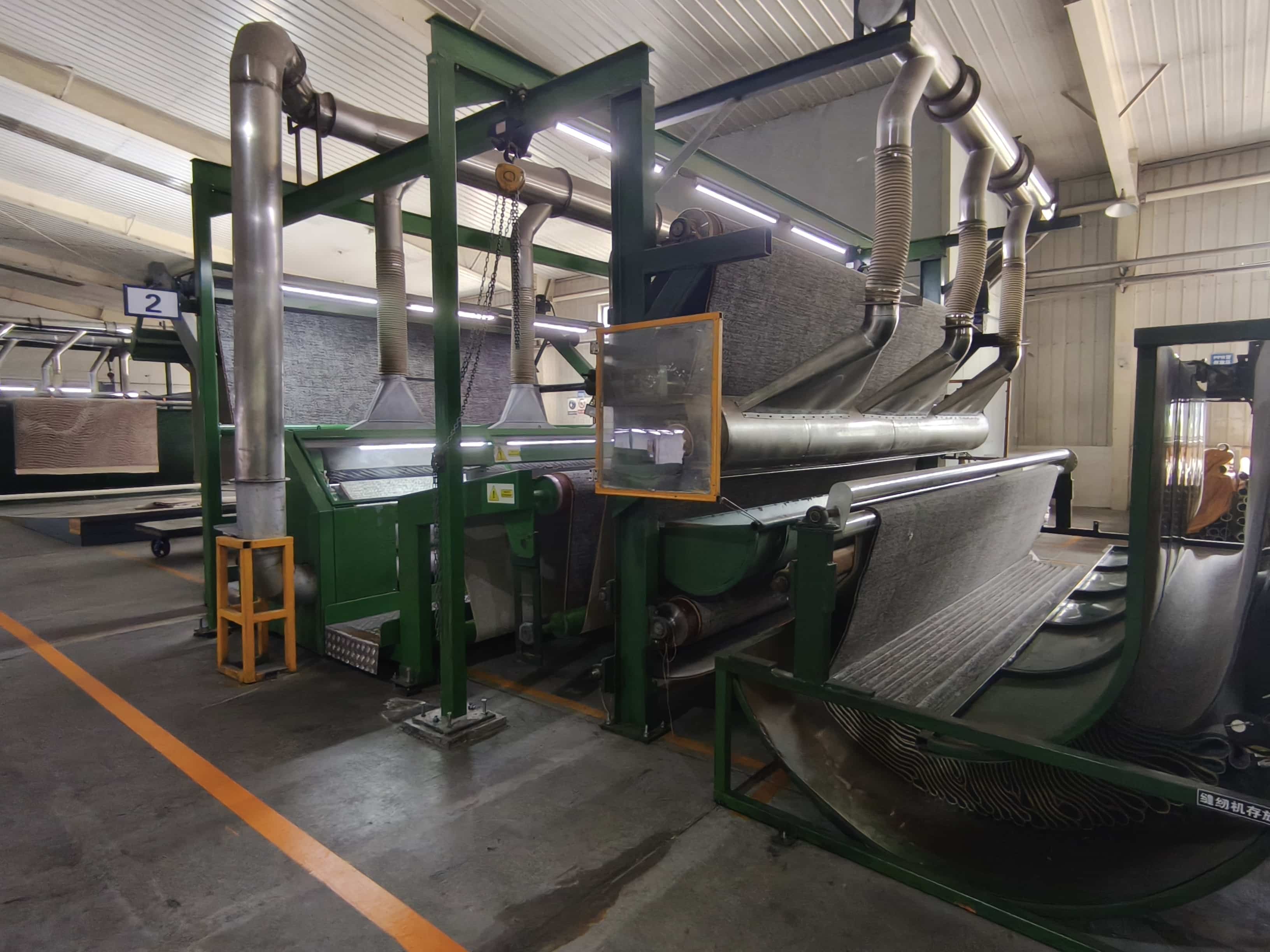 Wide-angle view of printed carpet manufacturing line with green frame and vacuum extraction system
