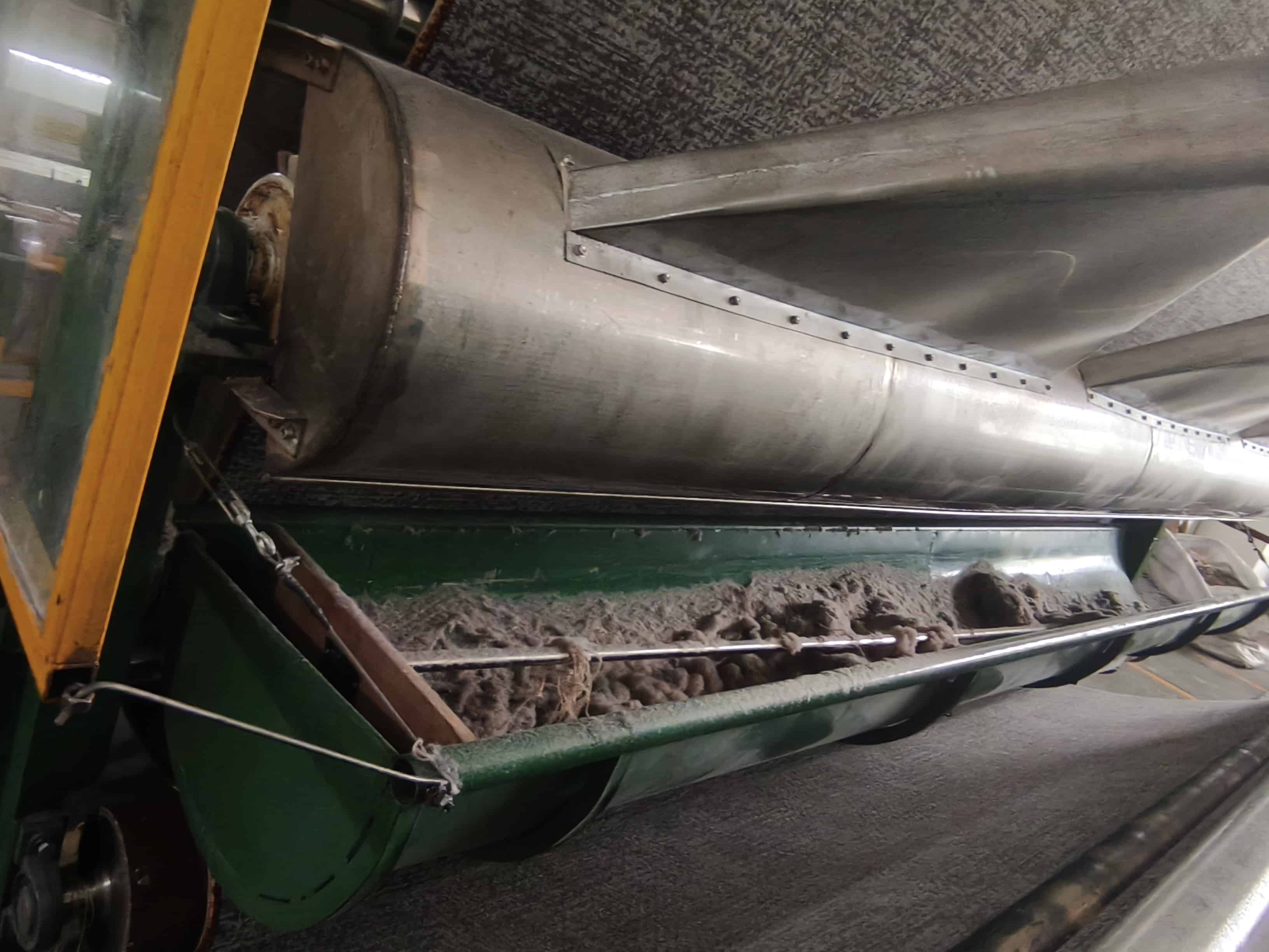 Close-up of printed carpet dust removal system with lint collection inside green framed machinery