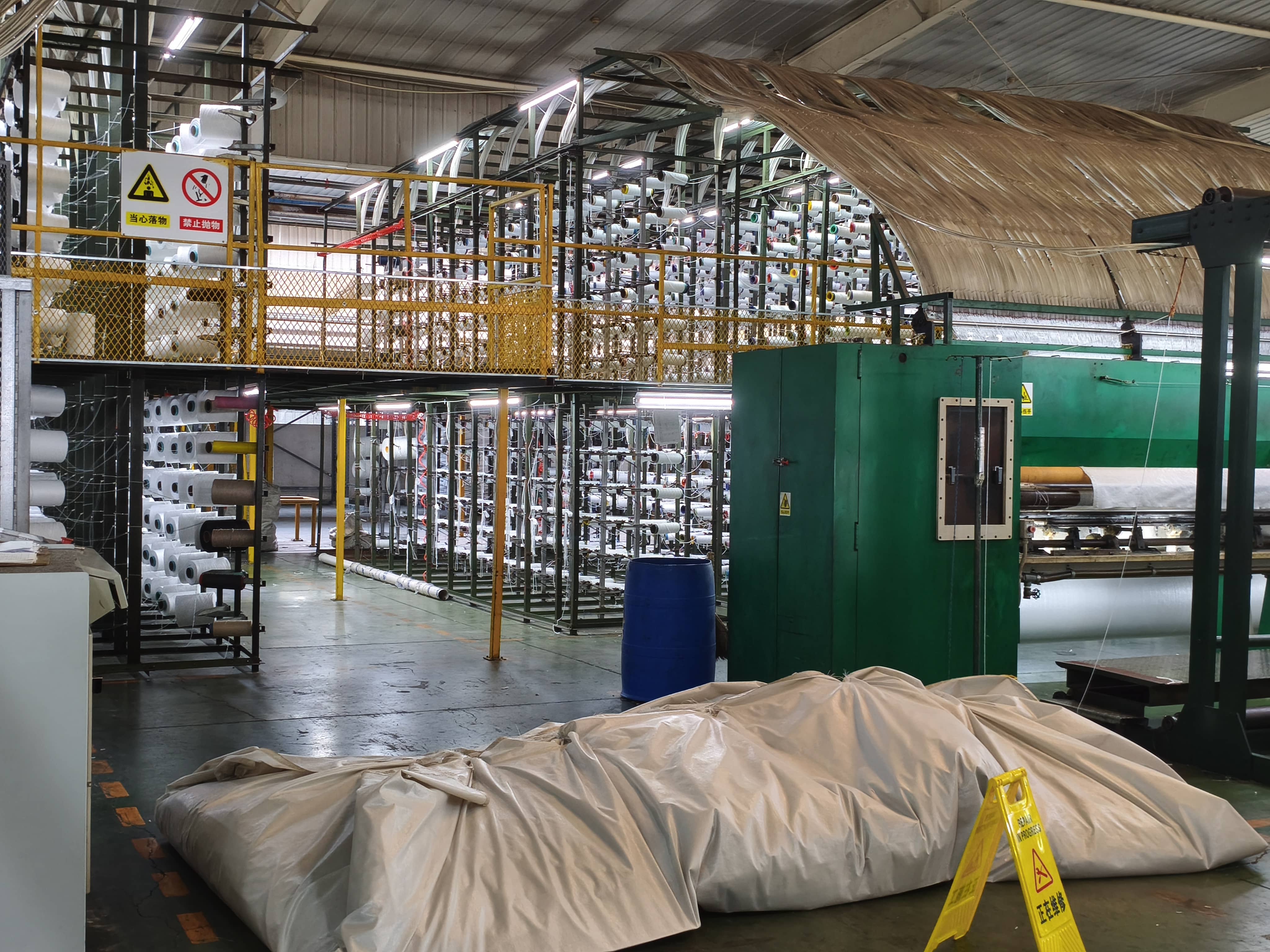 QIANQIAO yarn storage racks and green carpet manufacturing machinery in a modern factory
