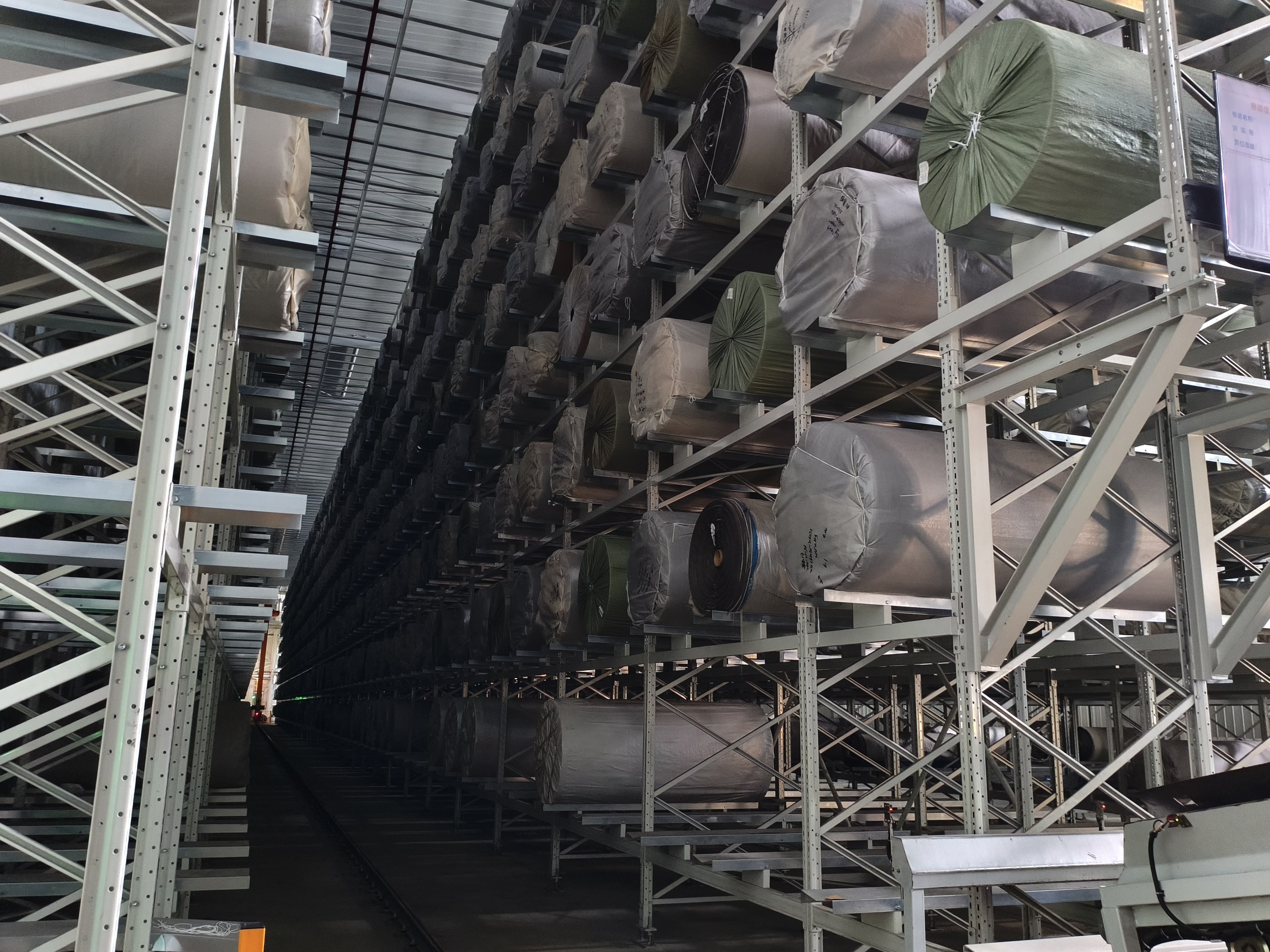 Qianqiao high-bay warehouse with multiple levels of carpet rolls stored on metal racks
