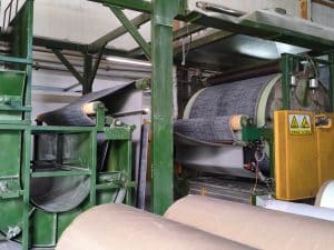A QianQiao carpet processing section with a rotating drum and precise guiding rollers for continuous fabric handling