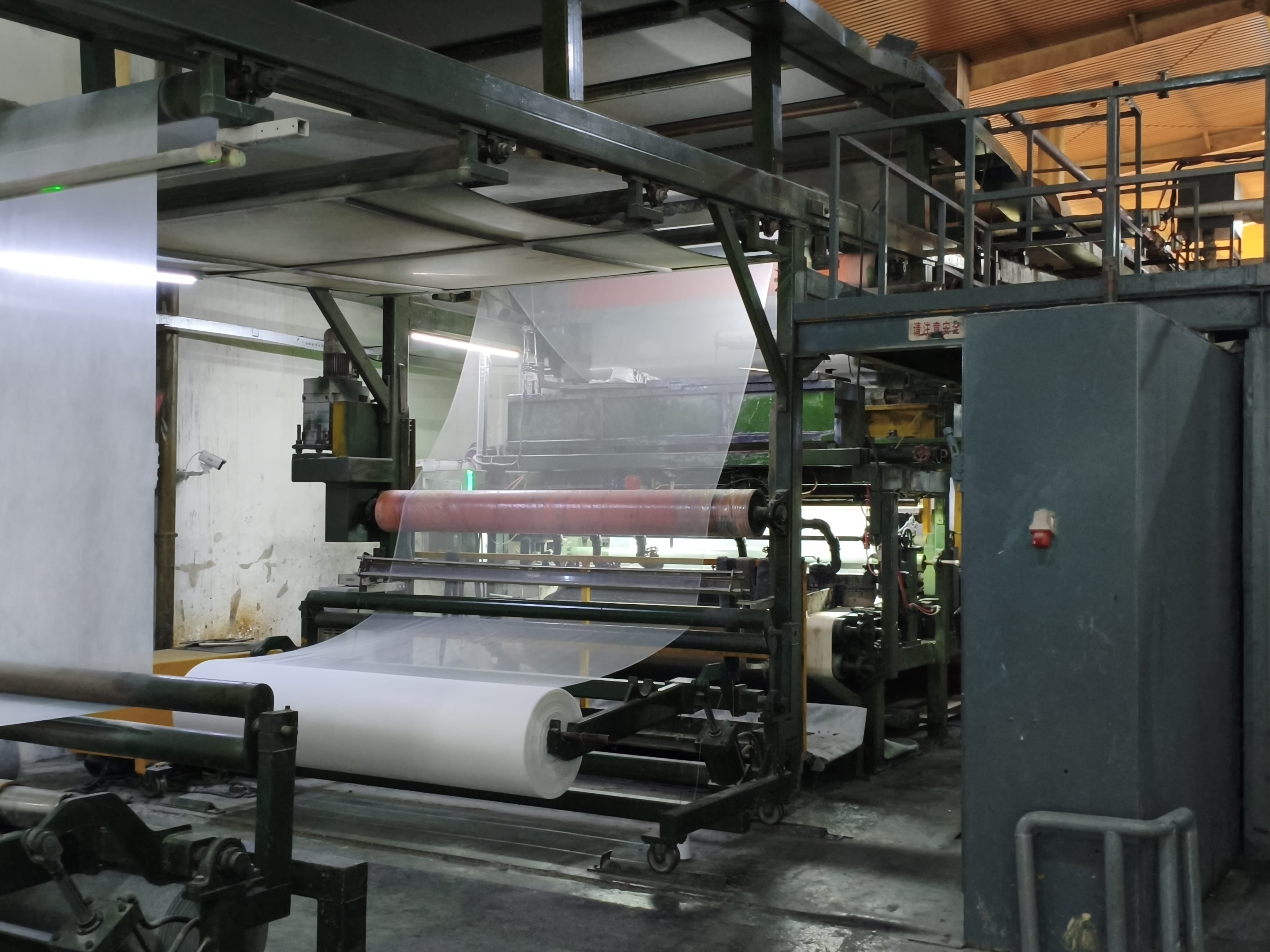 carpet production machine with layered white and pink material on output rollers