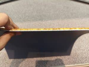 Hand holding an orange custom carpet tile, demonstrating side profile of pile and density